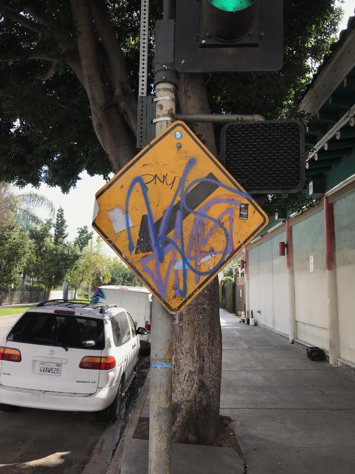 road sign with graffiti on it in the sun