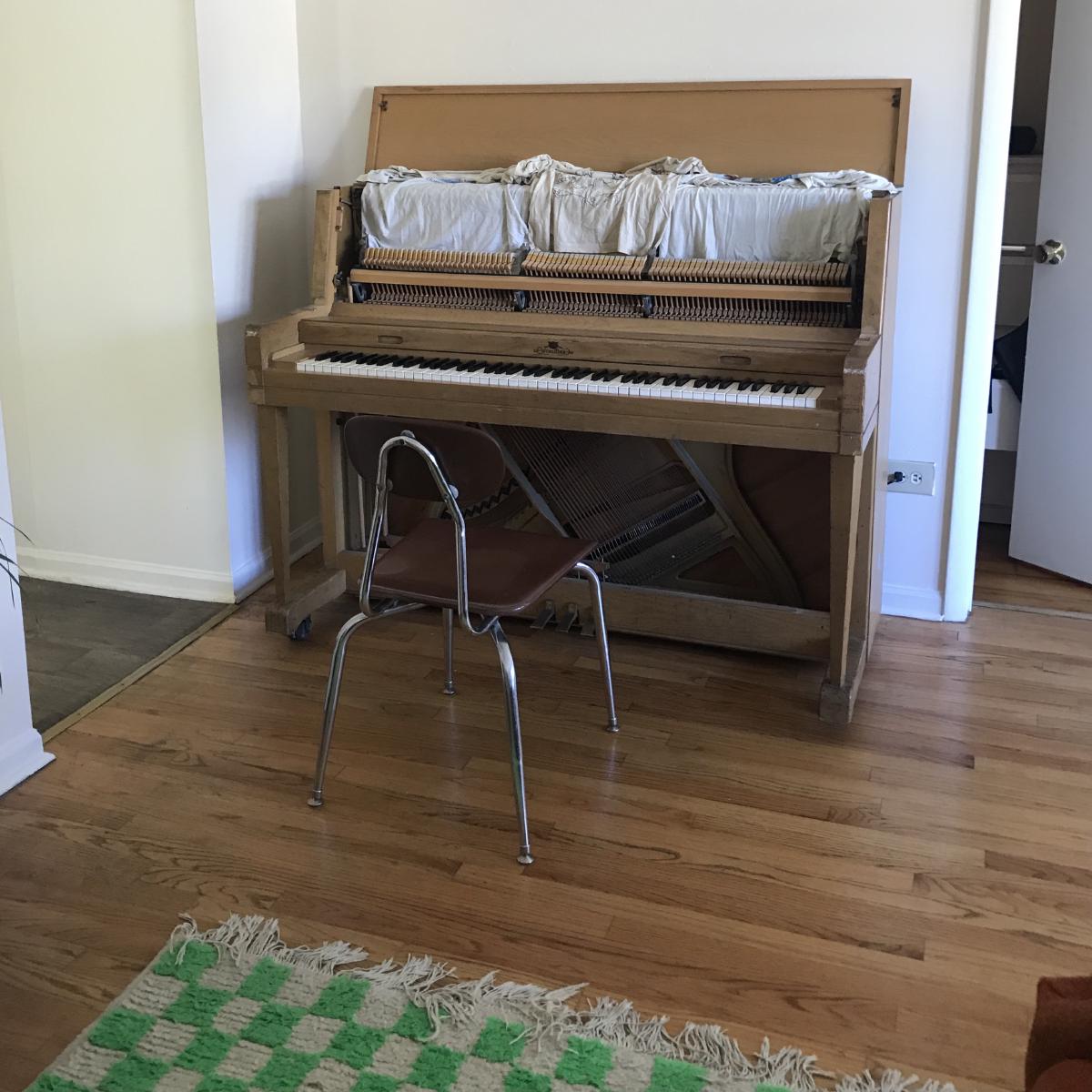 a natural wood piano and green checkered rug