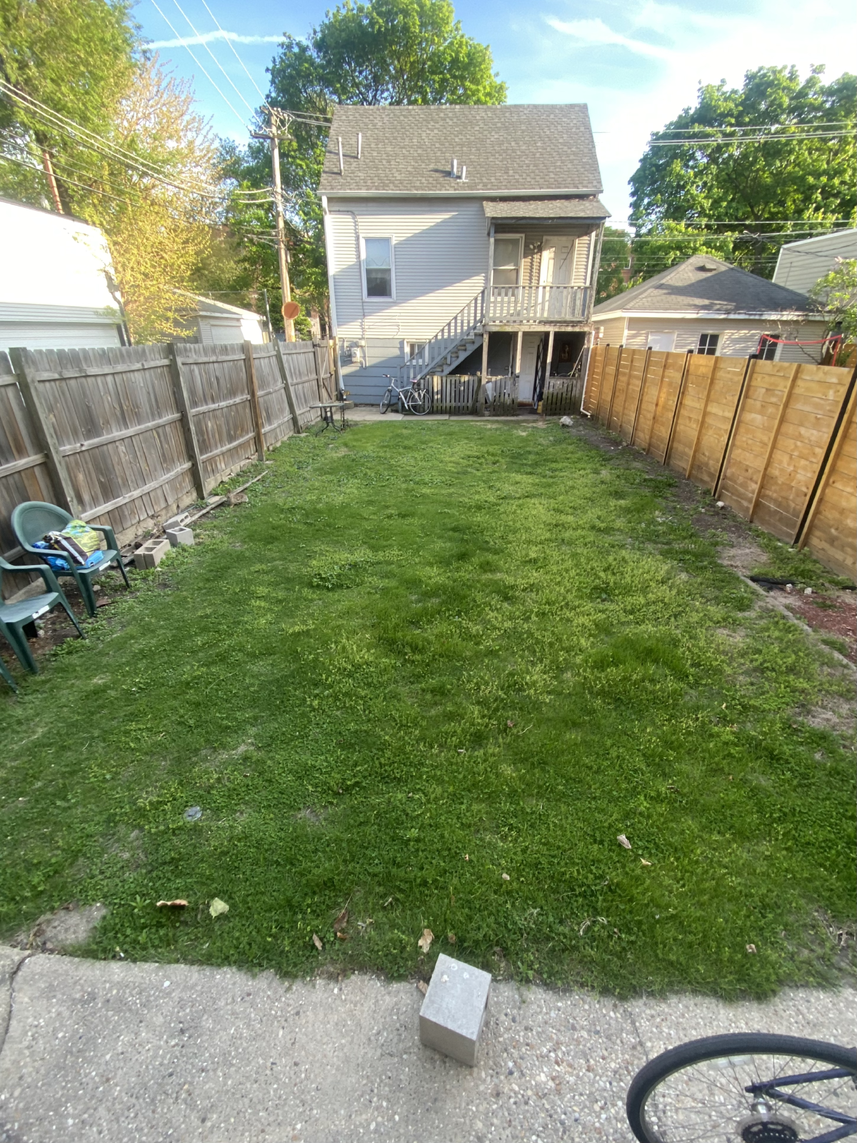 my grassy backyard with fences and neighbors coachhouse and my bike