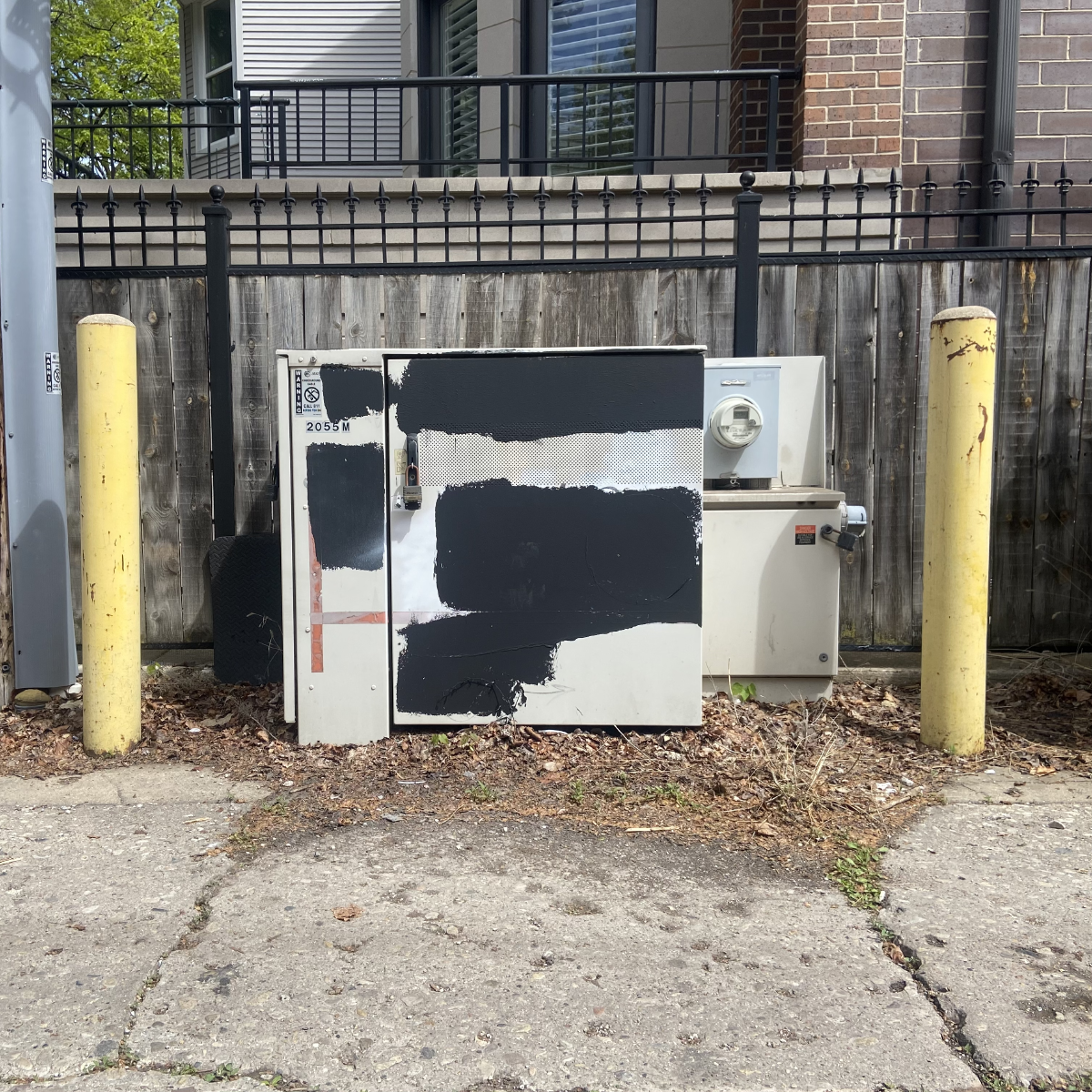 an electrical transformer with black paint splotches framed by two yellow poles